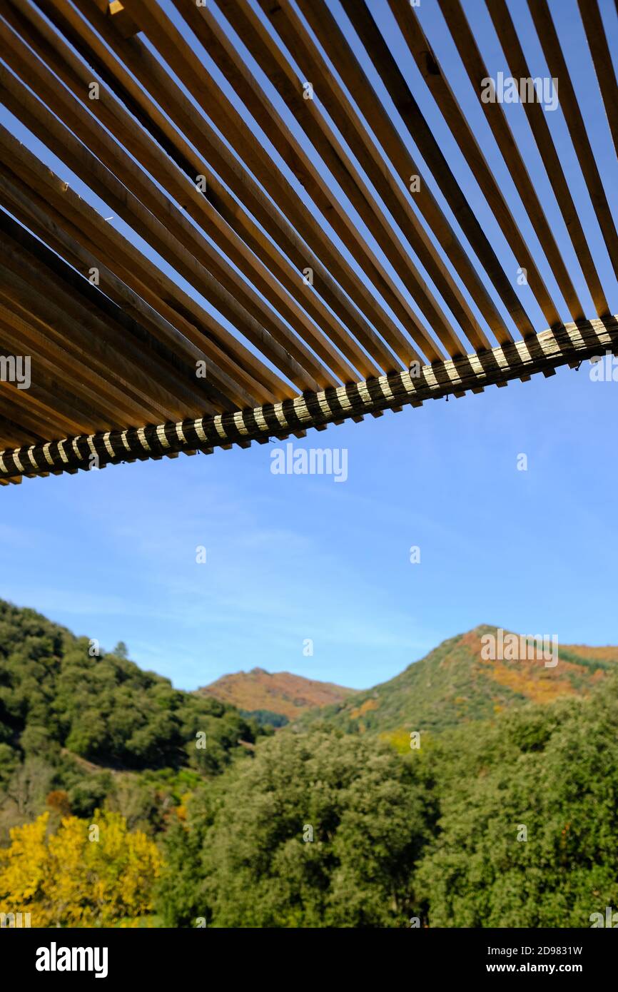 looking out across forested hills in autumn from under a wooden trellis on a terrace in the cevennes mountains in france Stock Photo