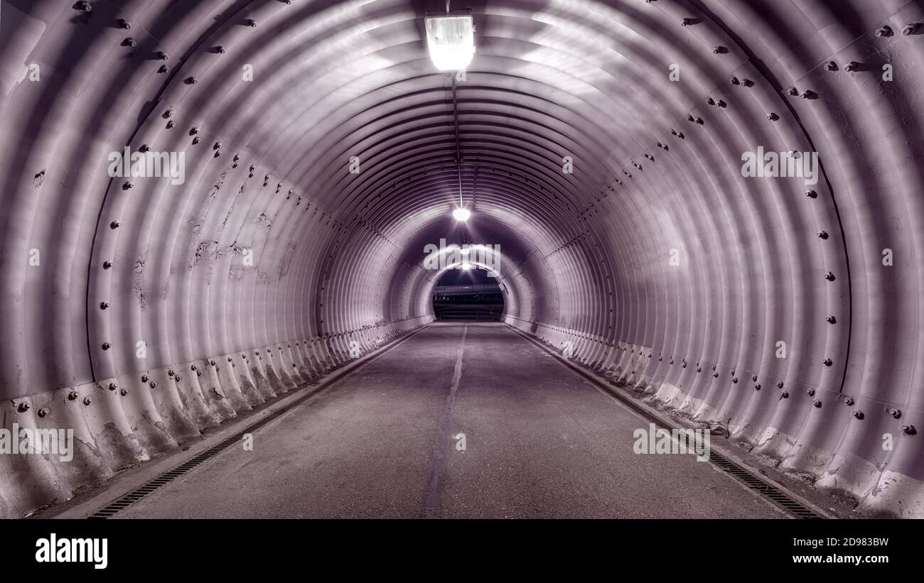 Large industrial stile illuminated tunnel with shadows on the walls. Wide angle view, one point perspective Stock Photo