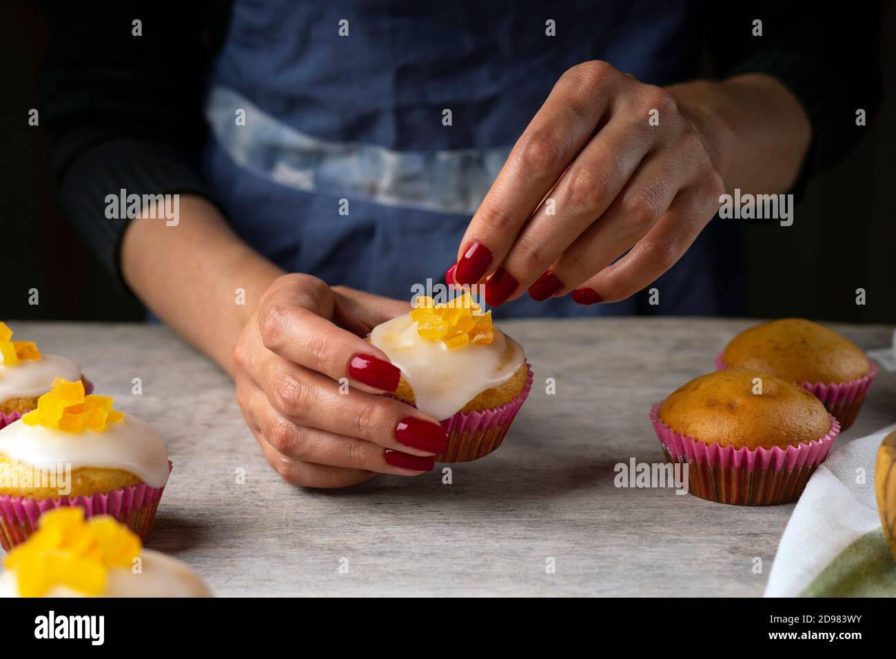 Confectioner' s female hands decorating the citrus muffins. Fresh muffins on a confectionery table Stock Photo