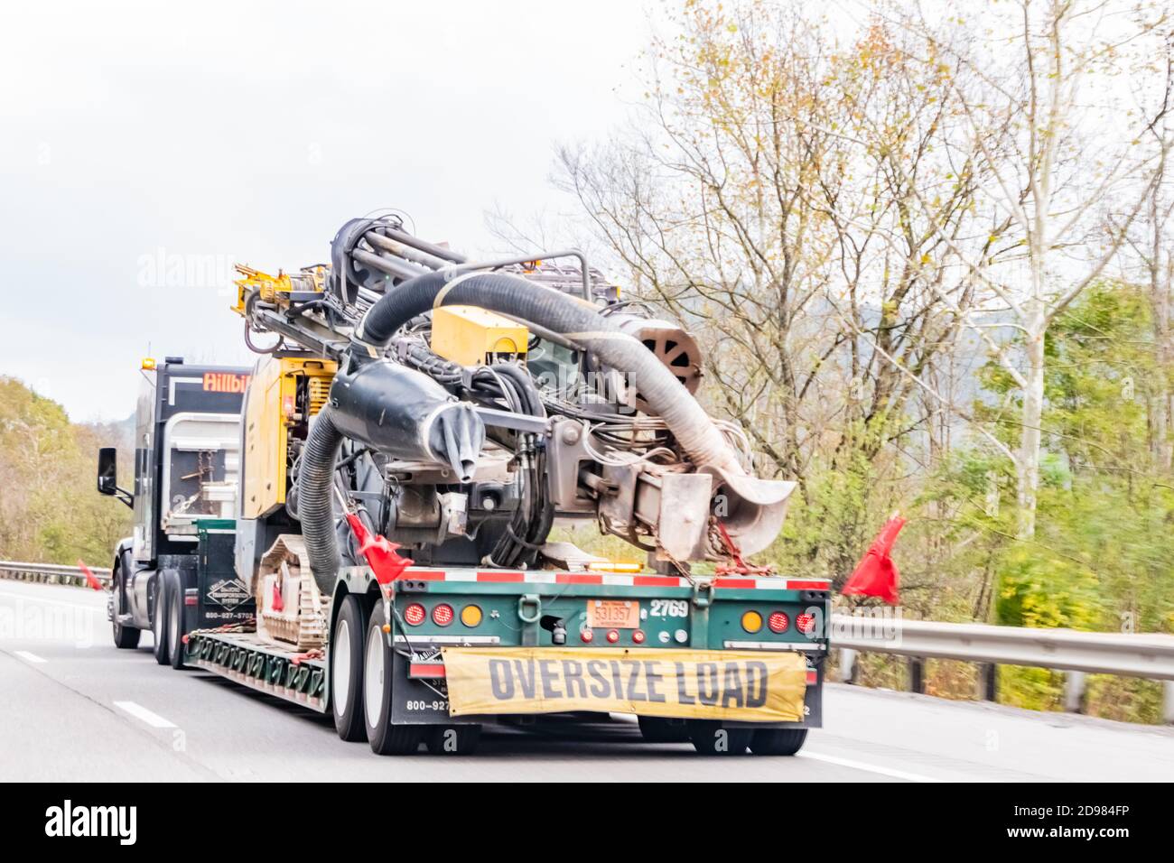 Rear view of wide load of huge Metal parts traveling the interstate on an overcast day. Stock Photo