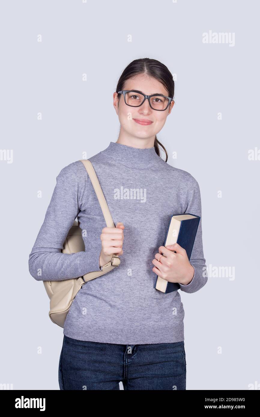 Confident student girl holding one books and carrying her backpack ...