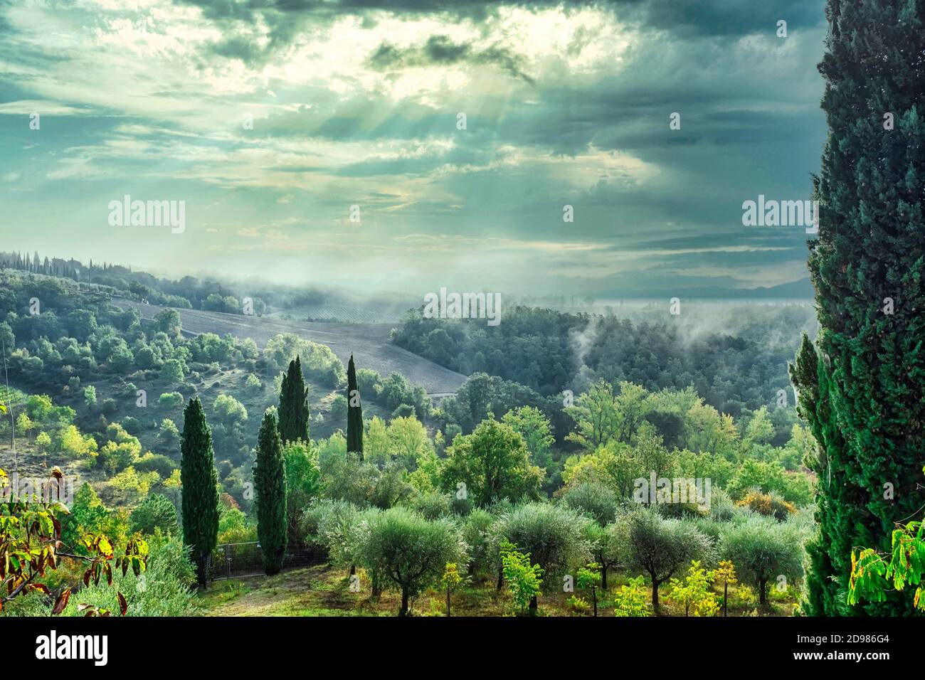 Picturesque green countryside in Tuscany Italy with sun shining through clouds. Stock Photo