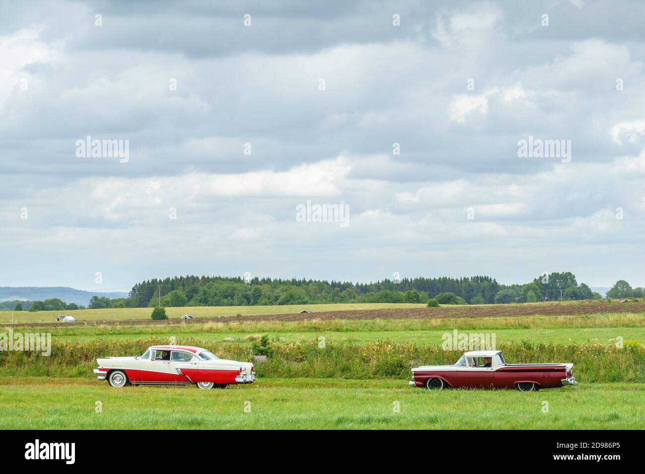Red-white Classic cars driving on a dirt road Stock Photo