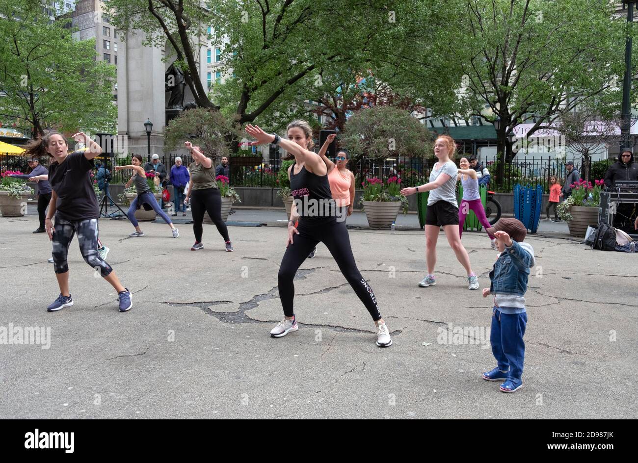 At an outdoor exercise class in Herald Square a young boy imitates the group leader. On Midtown Manhattan, New York City. Stock Photo