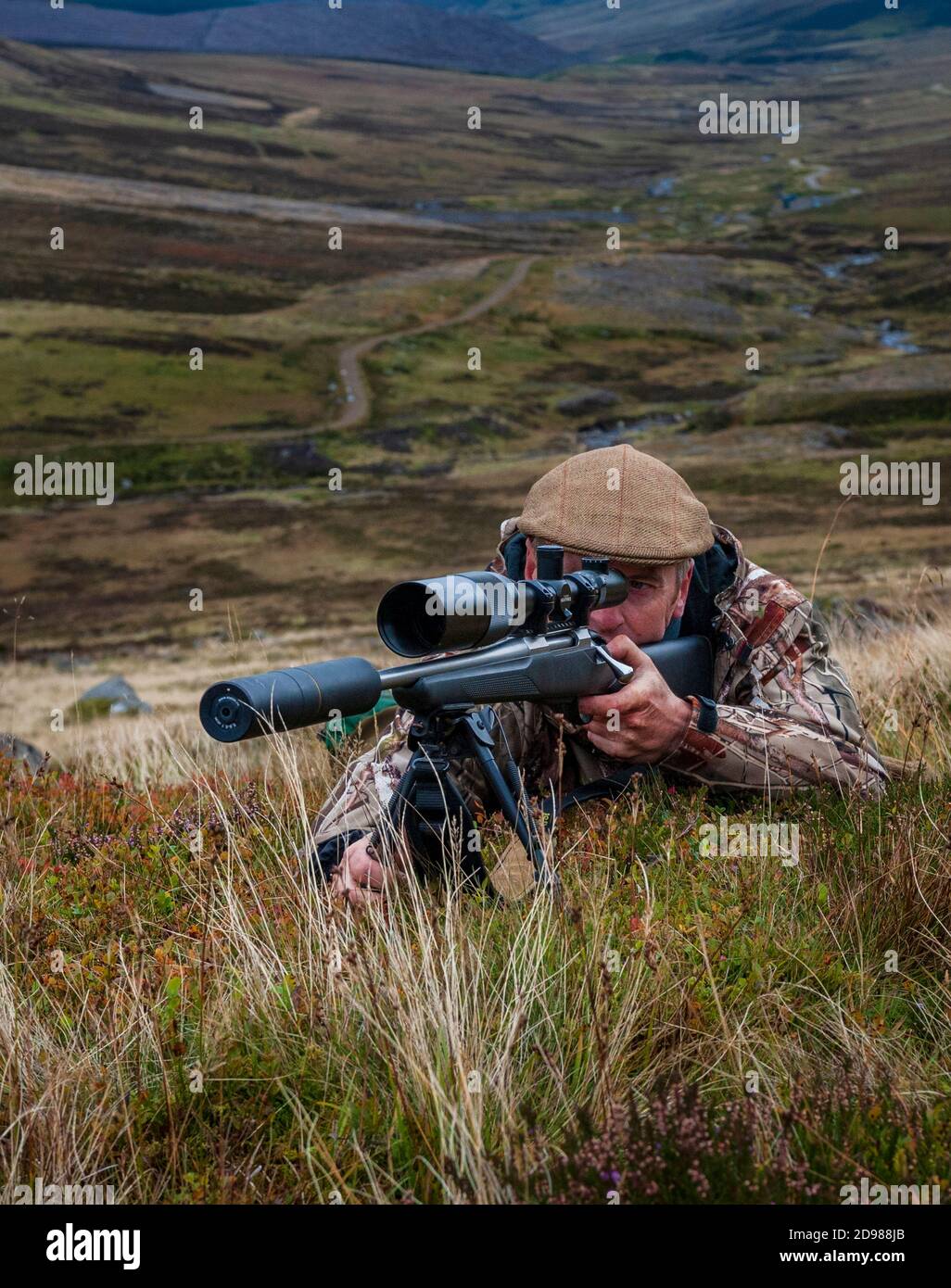 Scotland, UK – A deerstalker in the Scottish Highlands looking for a ...