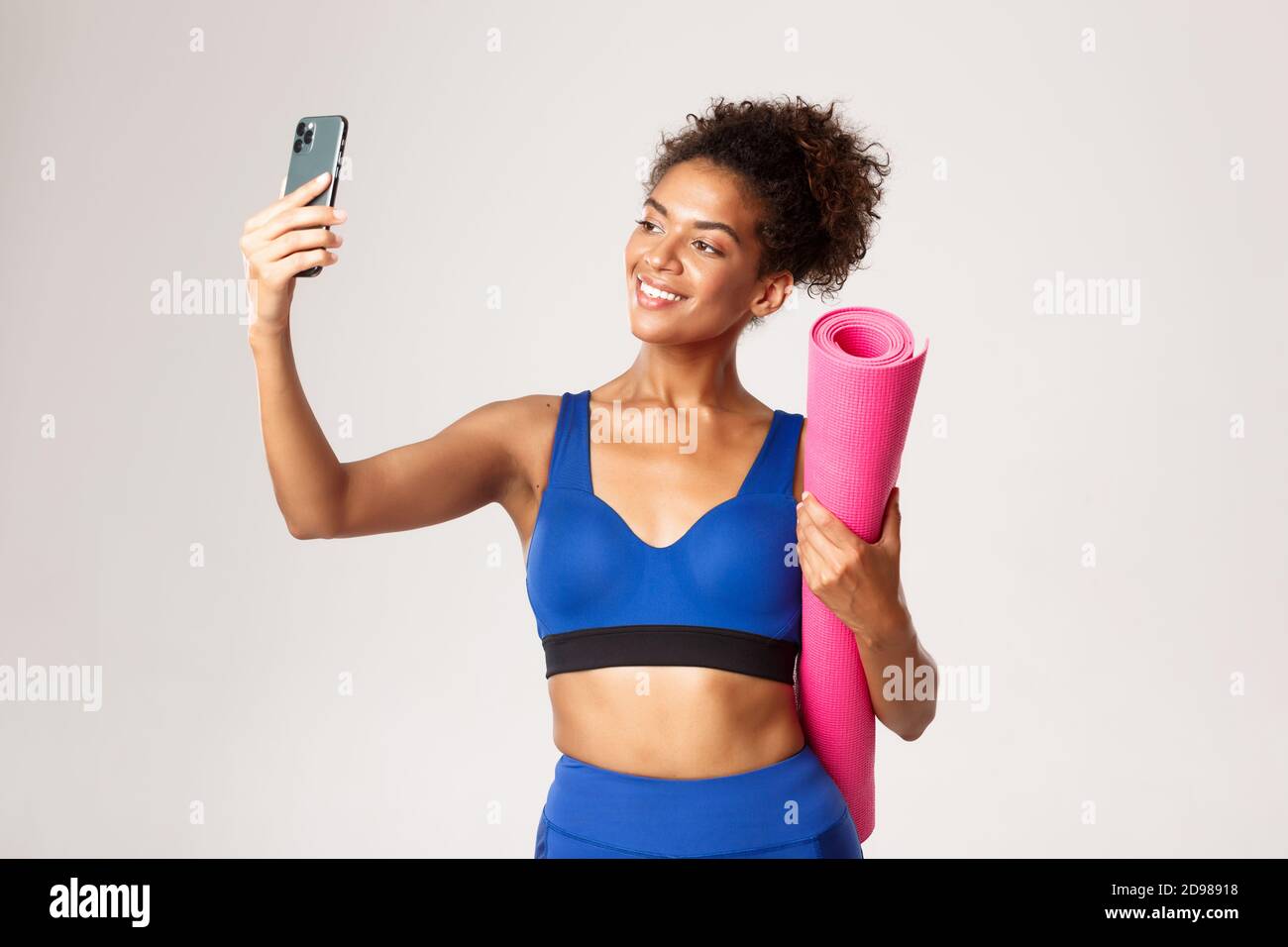 African American girl in gym outfit, holding a yoga mat. Beautiful