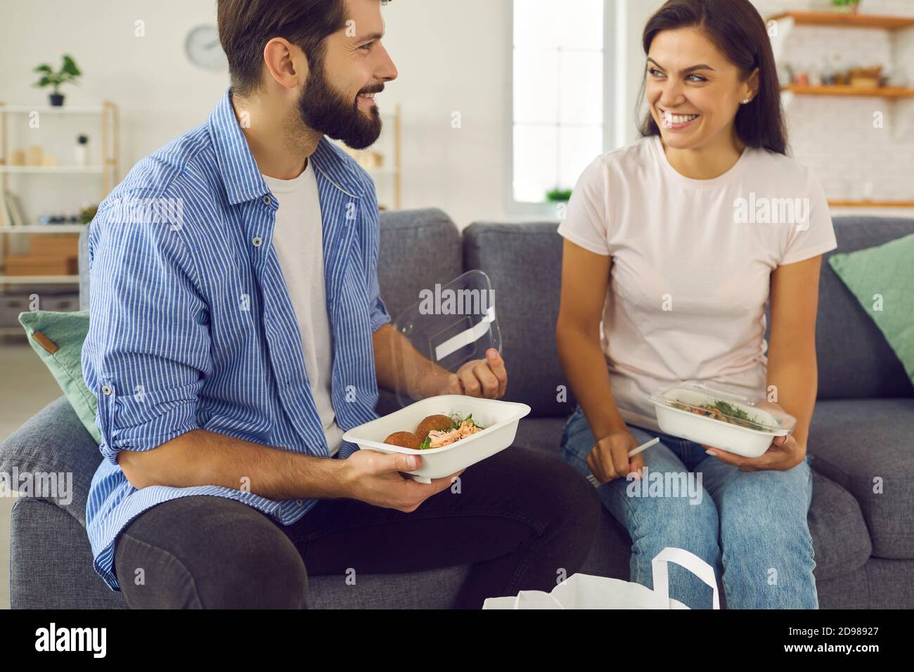 Happy young couple sitting on couch at home and having lunch ordered in meal delivery Stock Photo