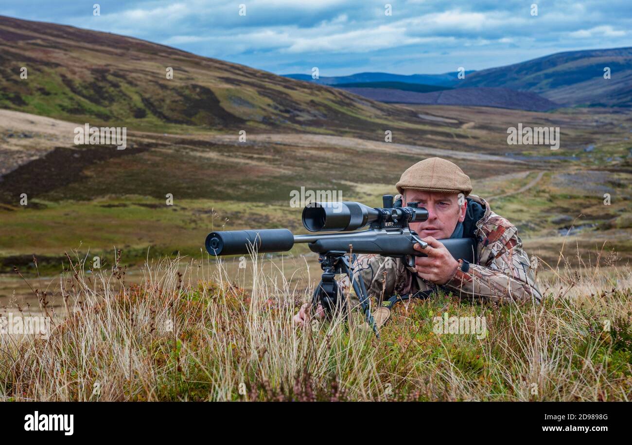 Scotland, UK – A deerstalker in the Scottish Highlands looking for a ...
