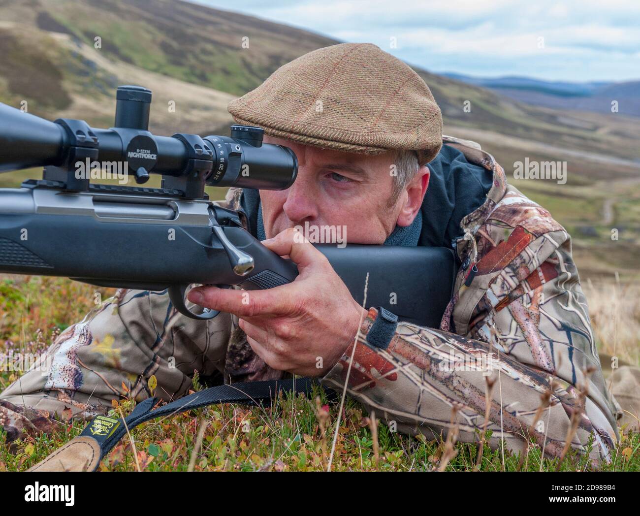 Scotland, UK – A deerstalker in the Scottish Highlands looking for a Red Deer Stag during the culling season Stock Photo