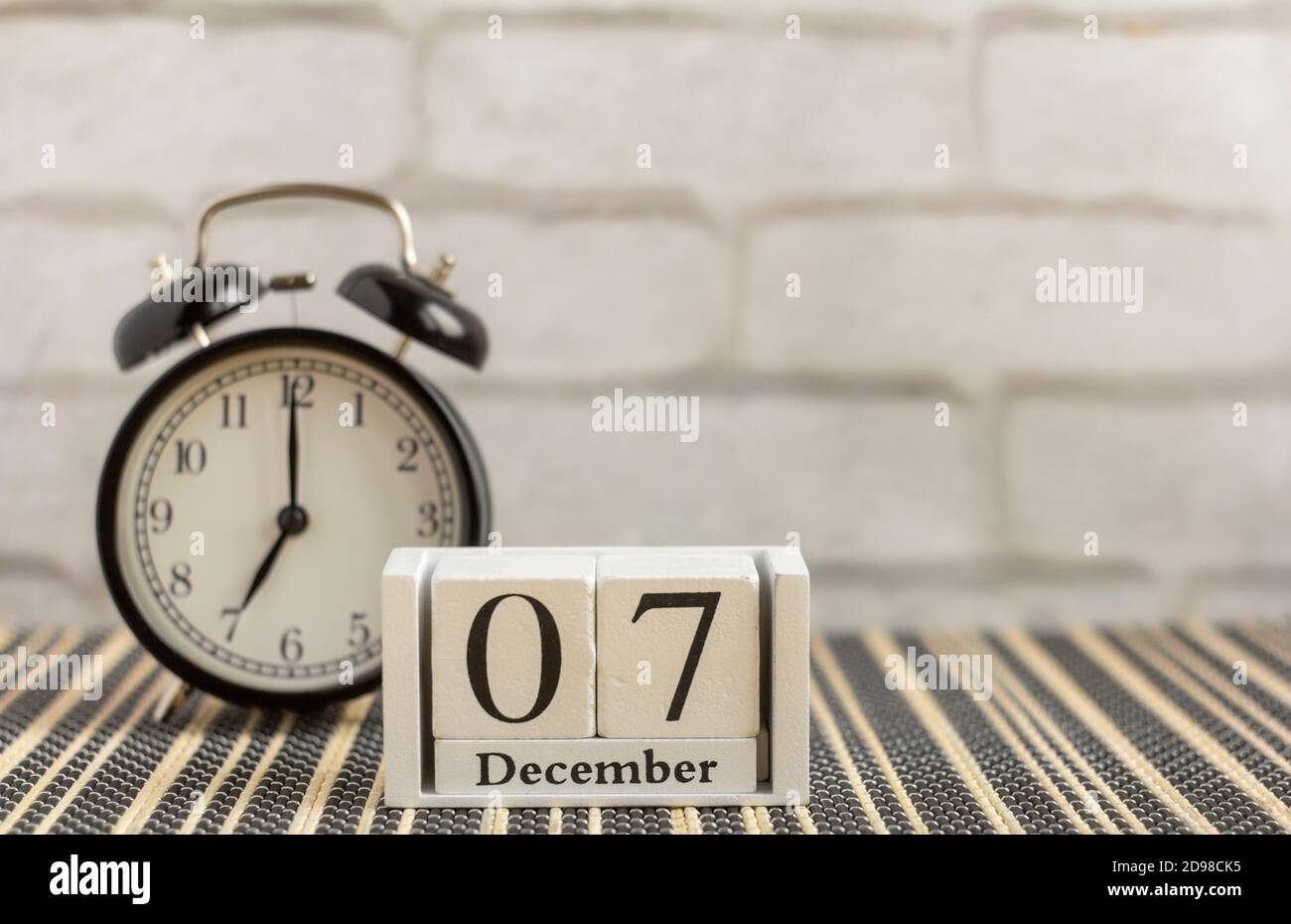 Calendar made of white wooden cubes and alarm clock on the table ...