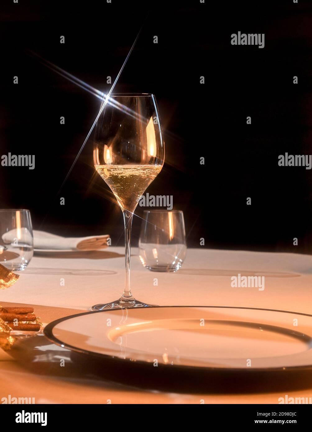 glass of champagne on table setting at restaurant, star light reflections on black background Stock Photo
