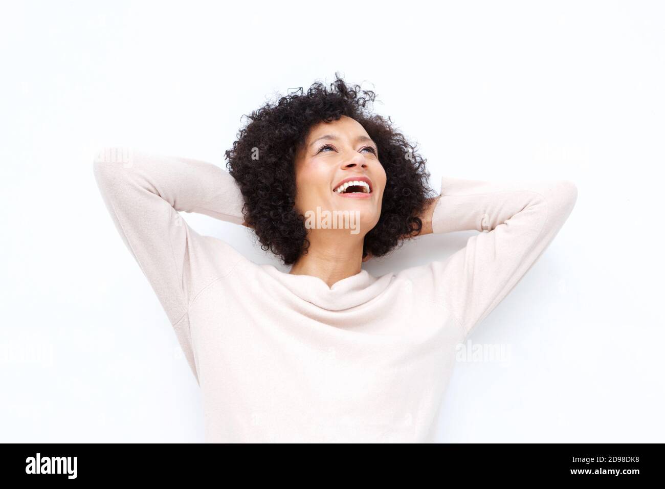 Close up portrait of happy older woman laughing with hands behind head against white backgorund Stock Photo