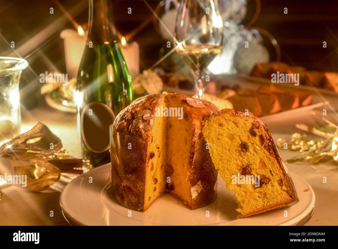 panettone on table set in Christmas style, in the blurred background bottle and glass of champagne and candles Stock Photo