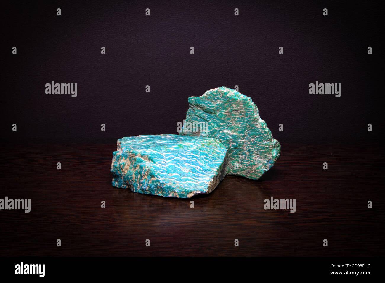 Two pieces of beautiful bright semiprecious mineral amazonite lying on a wooden surface Stock Photo
