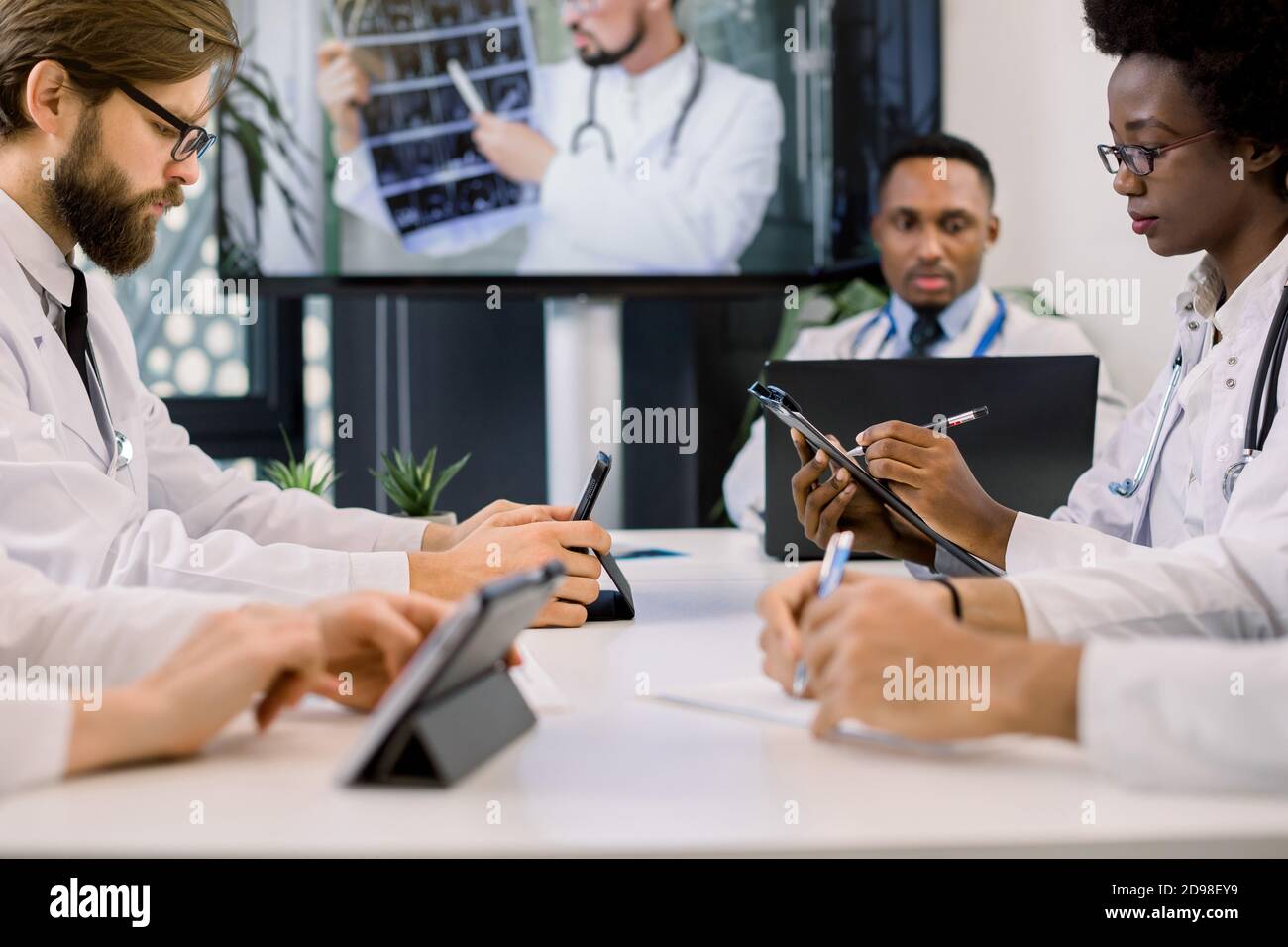 Cropped image of team of multiracial doctors using video screen projector during conference indoors, with their colleague discussing CT. African woman Stock Photo