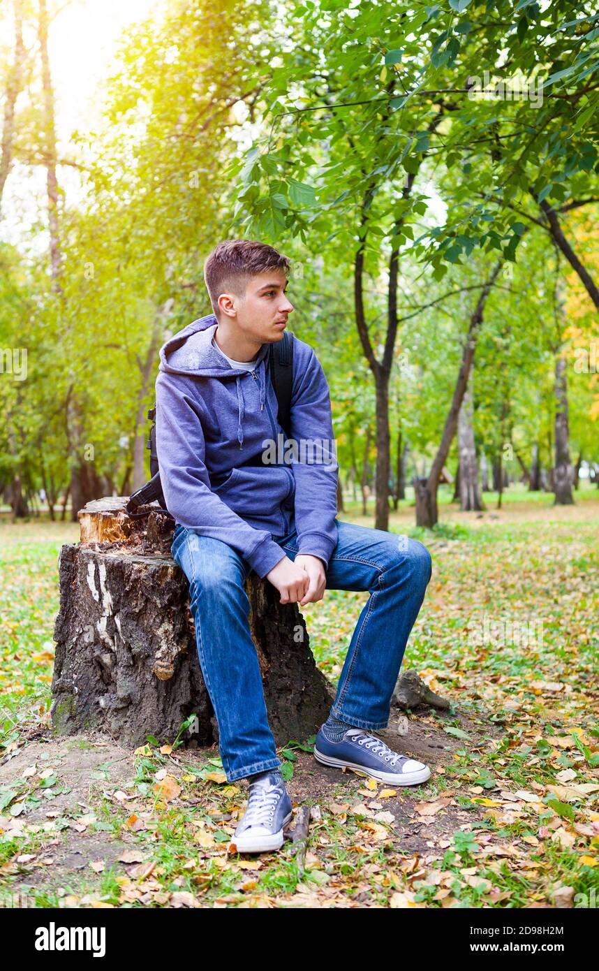Sad and Pensive Young Man sit in the Autumn Park Alone Stock Photo