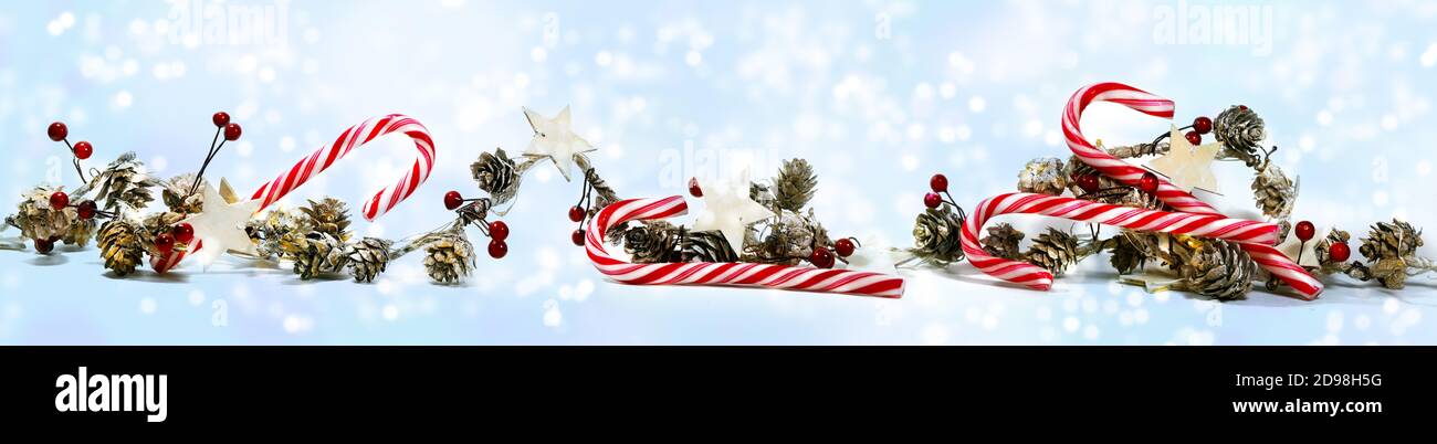 Panoramic Christmas banner with candy canes, cones, wooden stars and artificial red berries against a snowy light blue background with copy space, sel Stock Photo