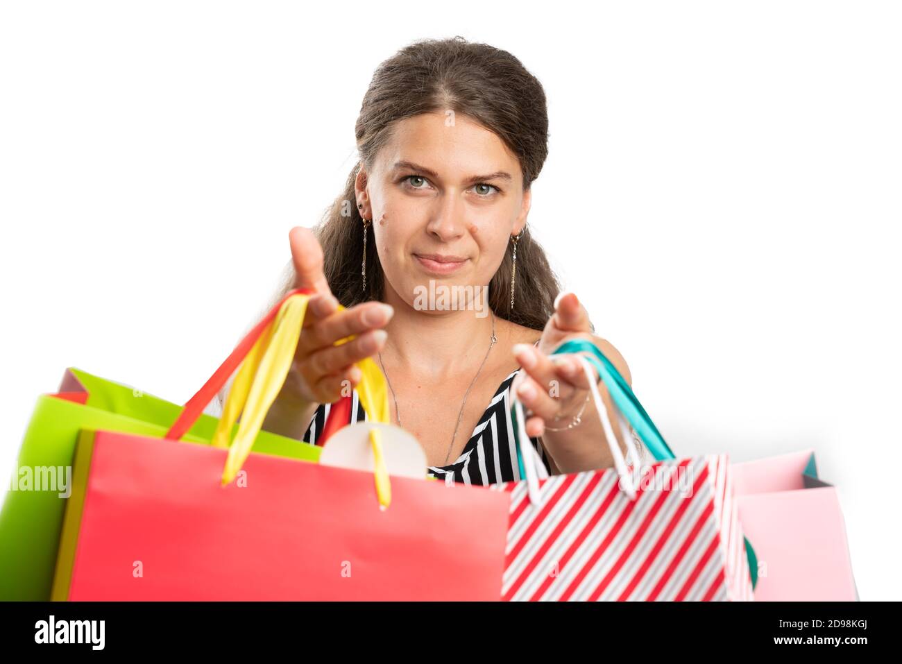 Close-up of female shopaholic adult model smiling offering shopping bags to camera as gift gesture isolated on white studio background Stock Photo