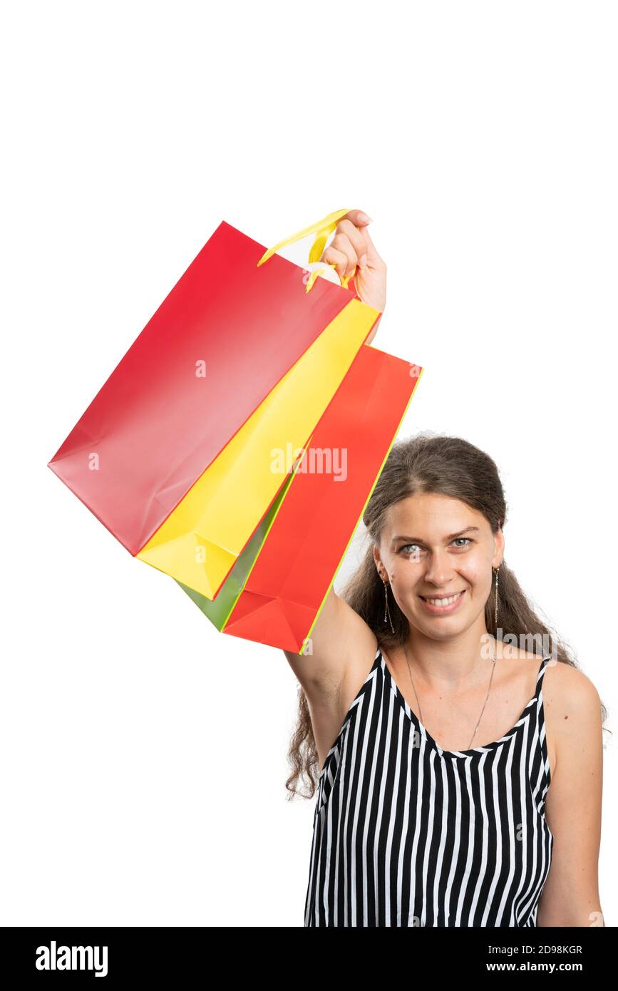 Smiling adult woman model holding colourful shopping bags wearing casual summer attire as presenting gesture consumerism buy concept isolated on white Stock Photo