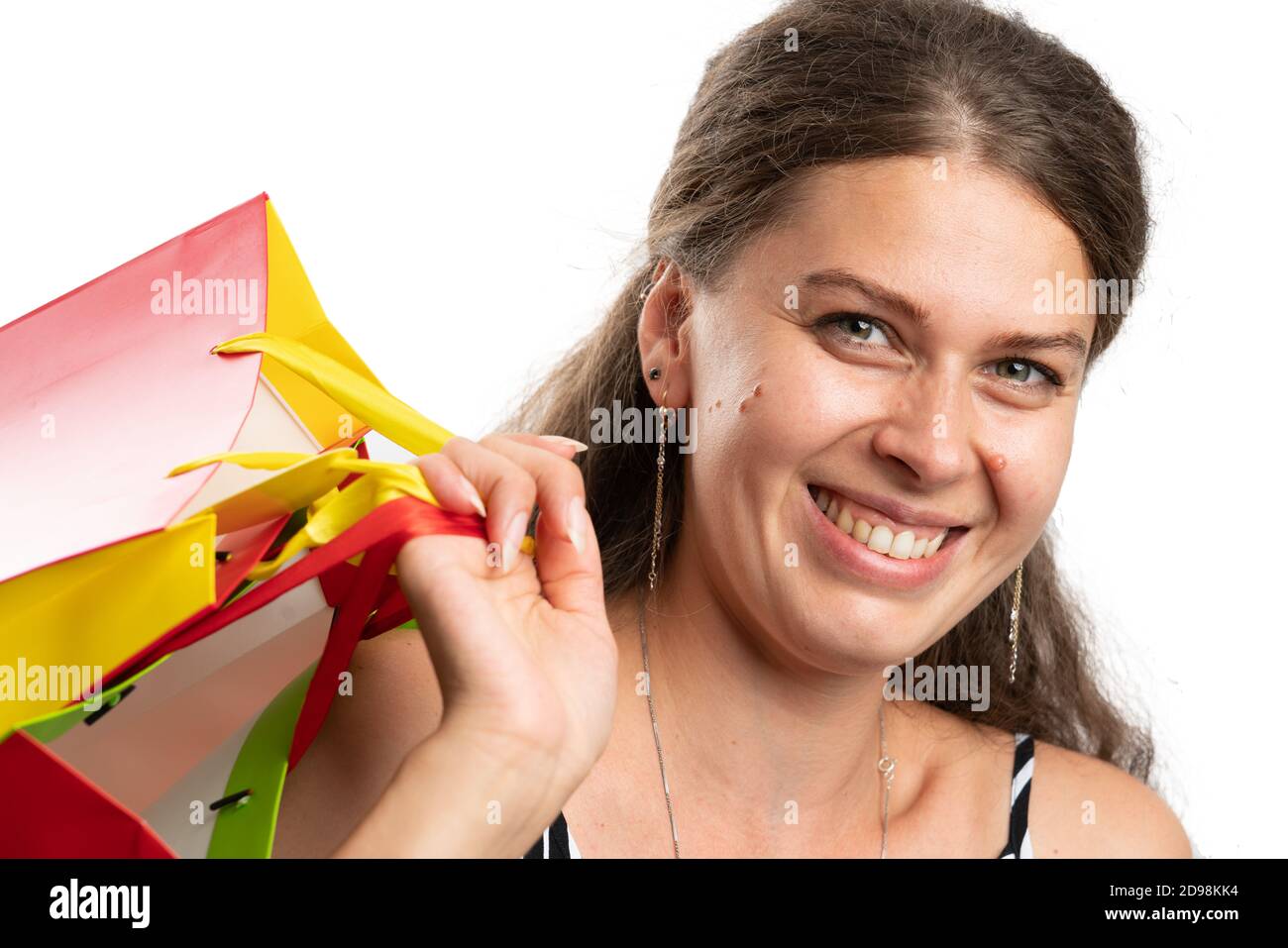 Close-up of happy cheerful woman making happy smiling friendly expression as carrying colourful shopping bags isolated on white studio background Stock Photo