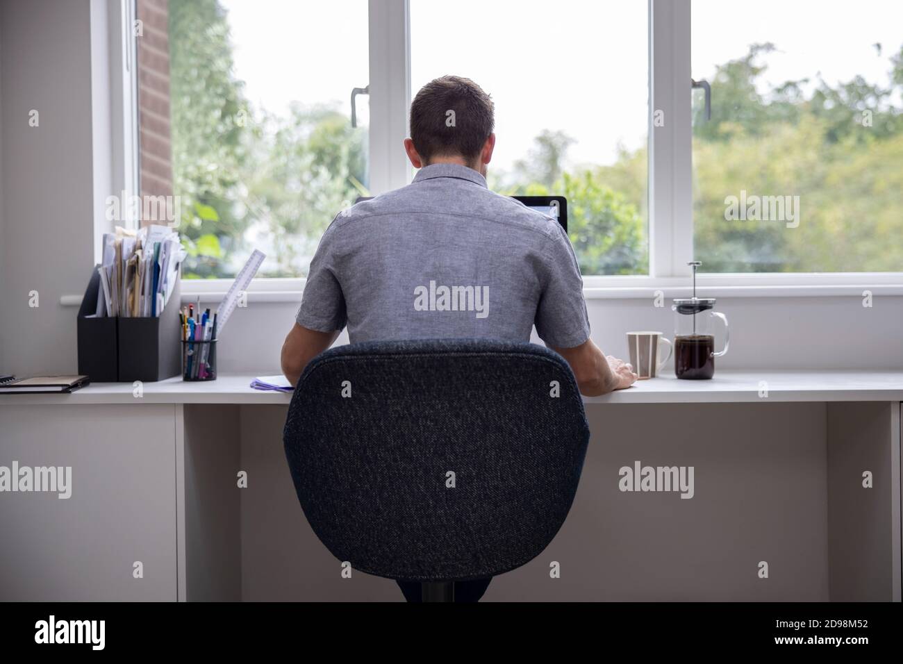 Rear View Of Man Working From Home On Computer  In Home Office Stock Photo