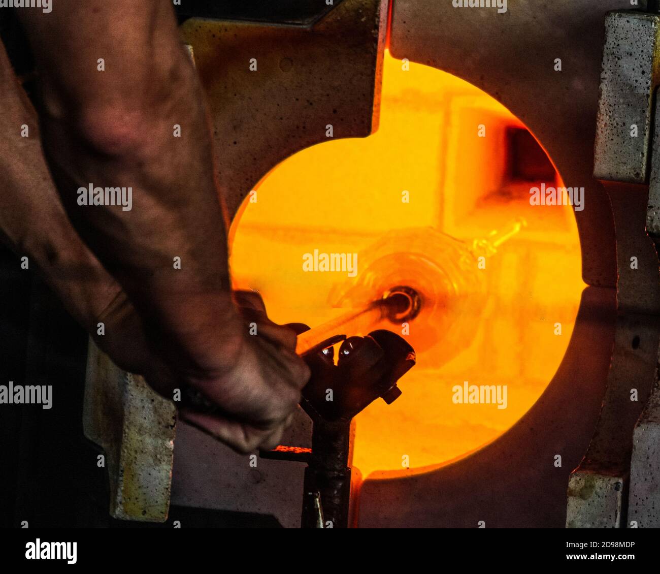 Glass blower with vase in kiln Stock Photo