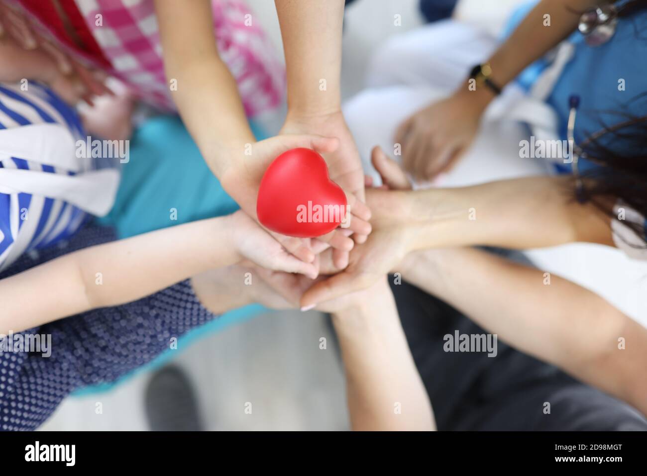 Hands of adults and children hold red heart in middle Stock Photo - Alamy