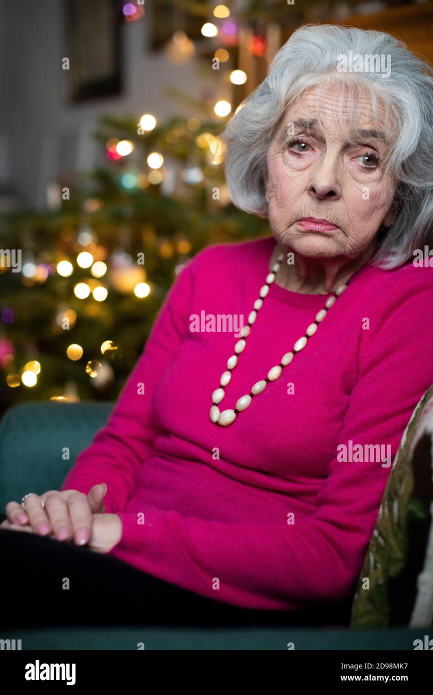 Sad And Lonely Senior Woman Unhappy About Spending Christmas At Home Alone Stock Photo