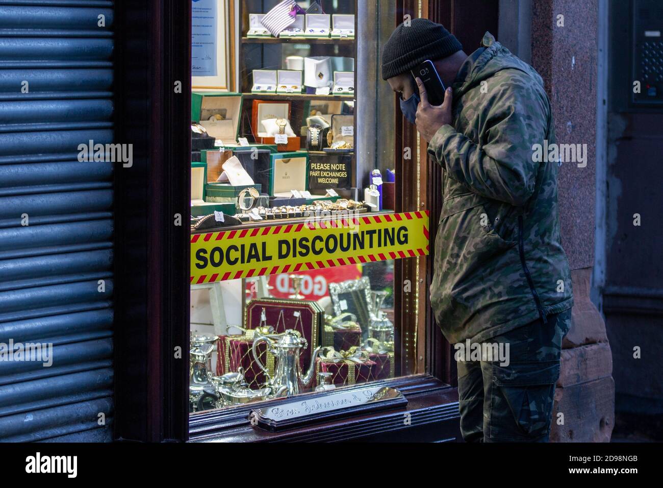 Social discounting sign in the style of the UK Government's coronavirus guidance. BIrmingham, UK. Man looks into Jewellery Shop, November lockdown Stock Photo