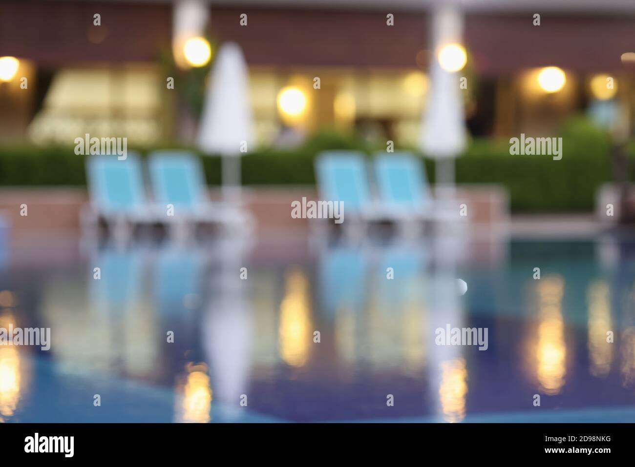 Bluired pool background with sun loungers and umbrellas in evening Stock Photo