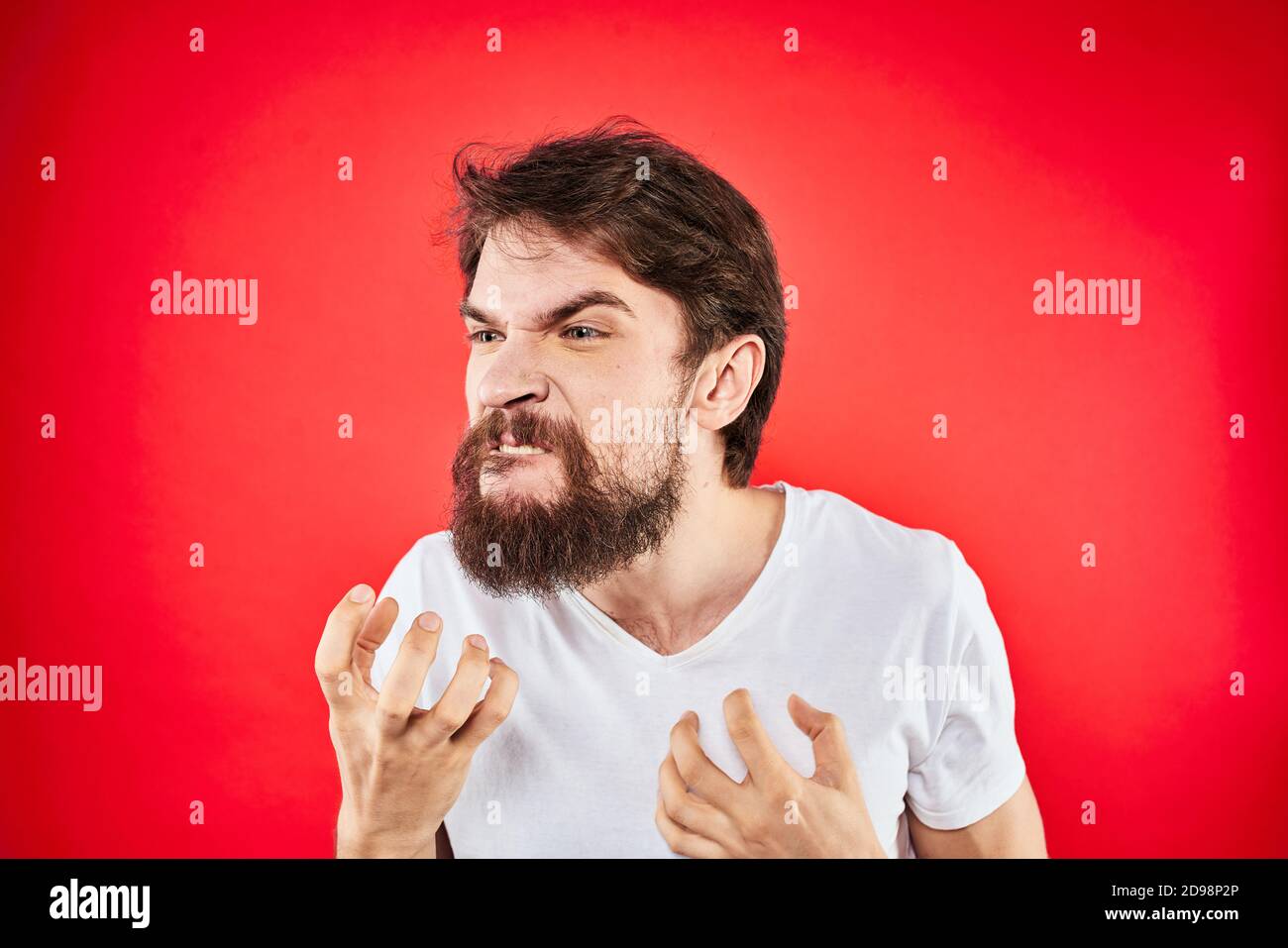 Emotional bearded man gestures with his hands in a white T-shirt ...
