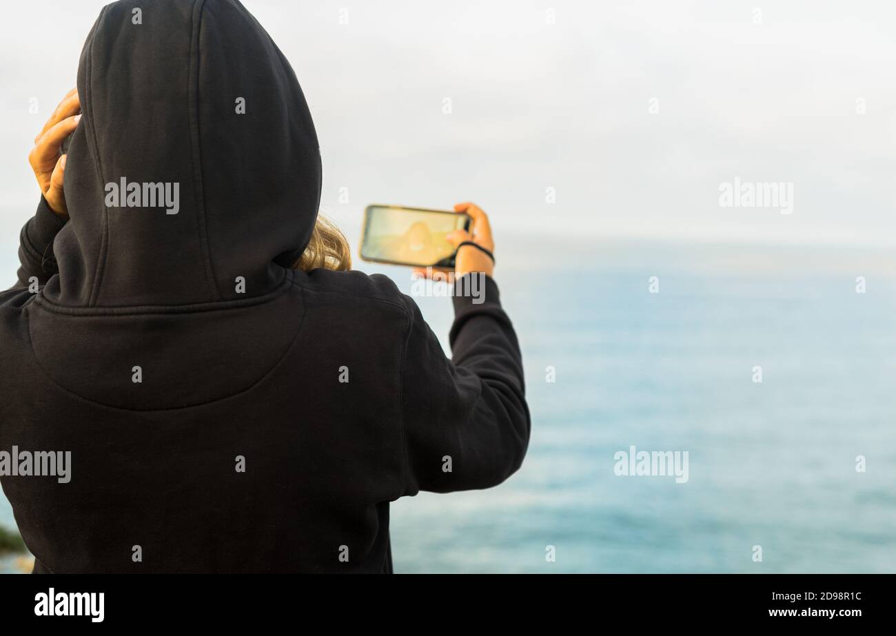 Backshot of a young female making a selfie on the scenic background