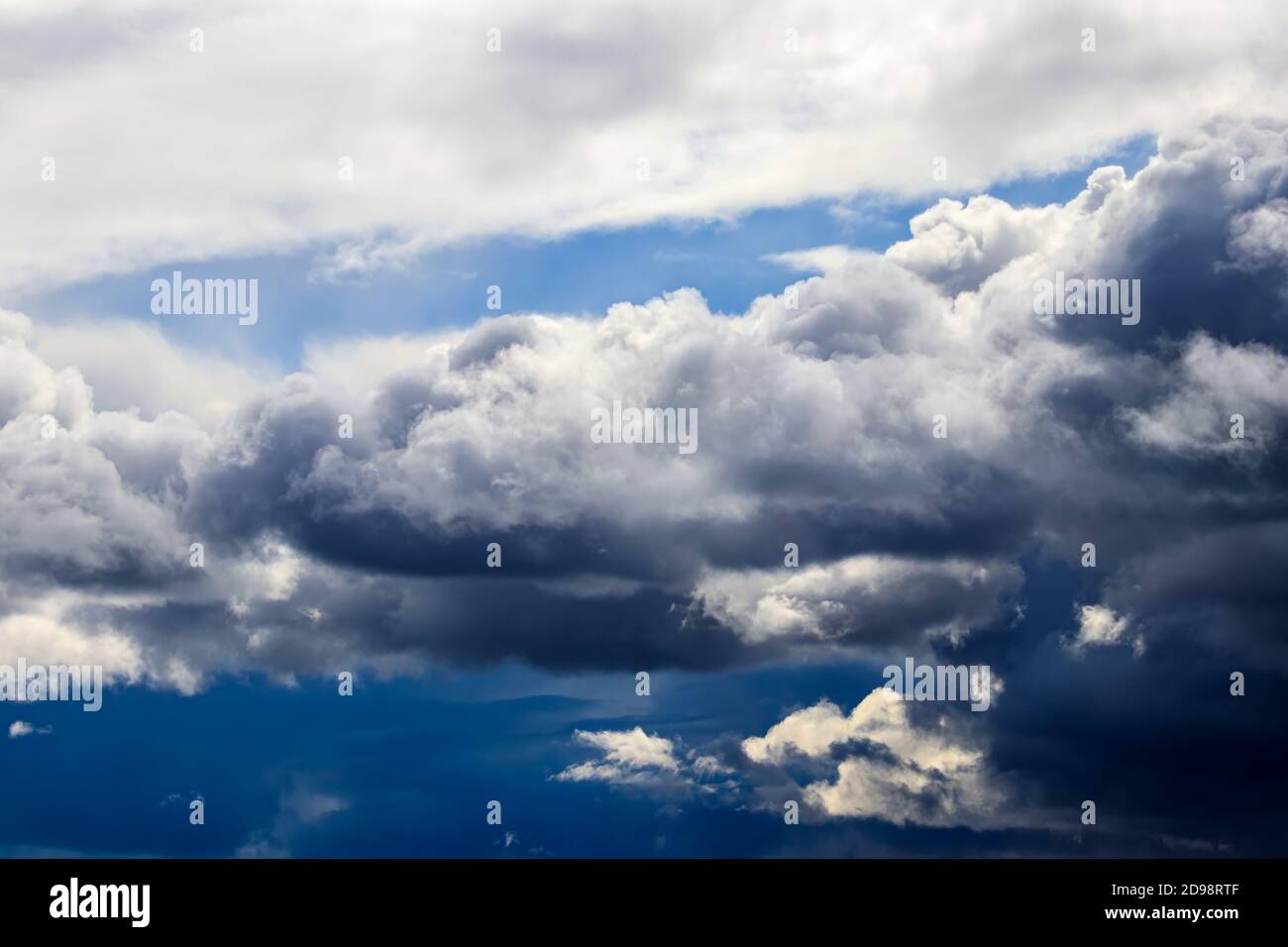 Bright blue sky with dramatic cumulus clouds lit by the daytime sun ...