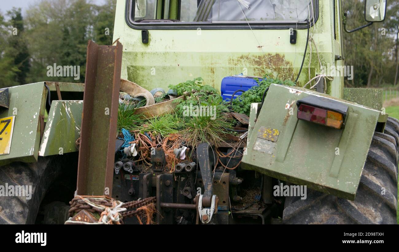 Abandoned, green, Mercedes-Benz tractor with weeds growing on it in a field. Stock Photo