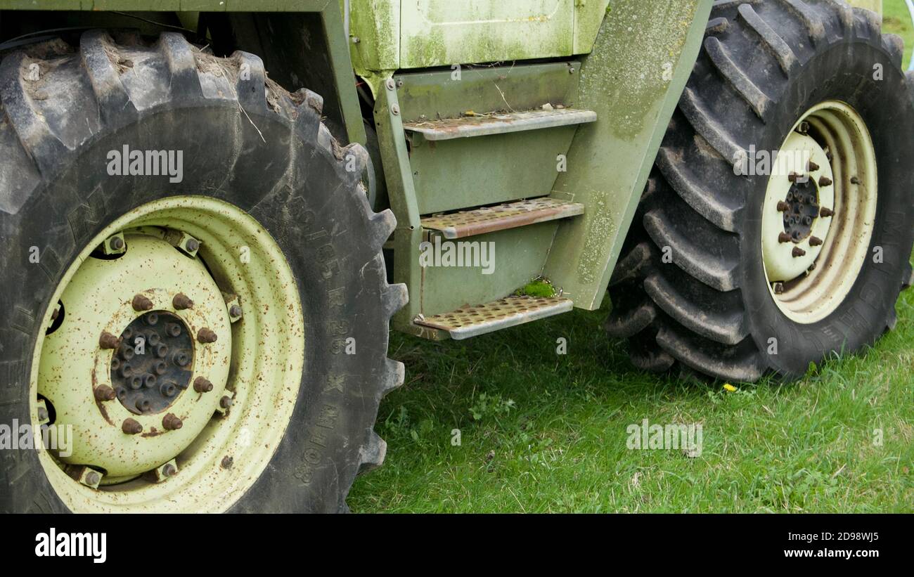 Close up of large black tractor wheels. Green tractor parked in farmer