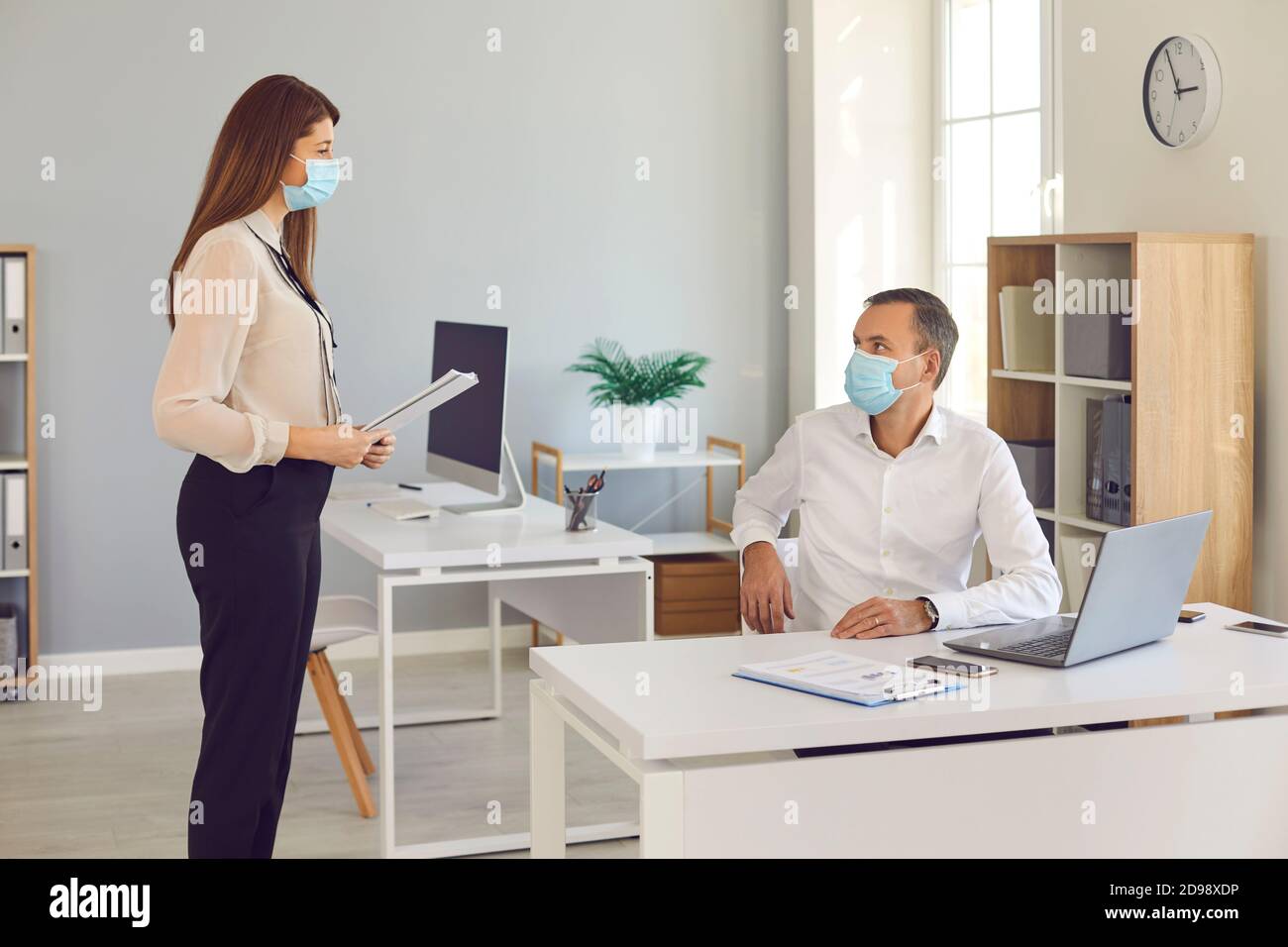 Company workers working together in the office wearing face masks and ...