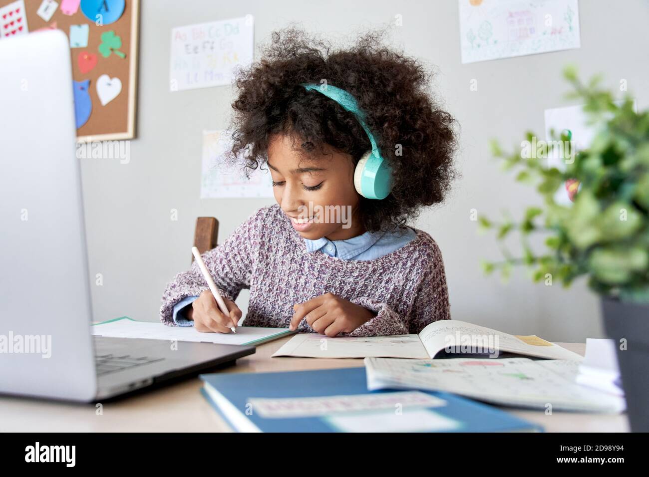 African school kid girl wearing headphones virtual distance learning at home. Stock Photo