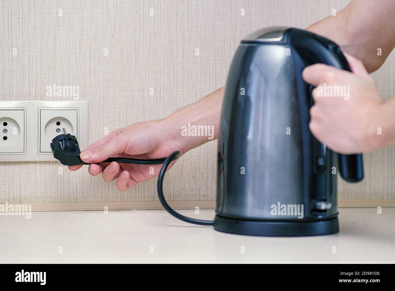 https://c8.alamy.com/comp/2D98YD6/the-man-holds-the-electric-power-in-his-hand-and-connects-the-kettle-to-the-outlet-2D98YD6.jpg