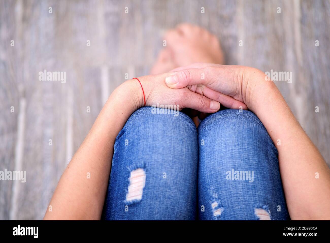 The girl is sitting with her hands folded in her lap. Forced seclusion during the quarantine period. In order to avoid the spread of the epidemic Stock Photo