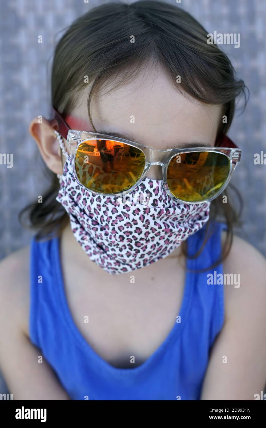 Beautiful little girl wearing a protective mask made of fabric with ...
