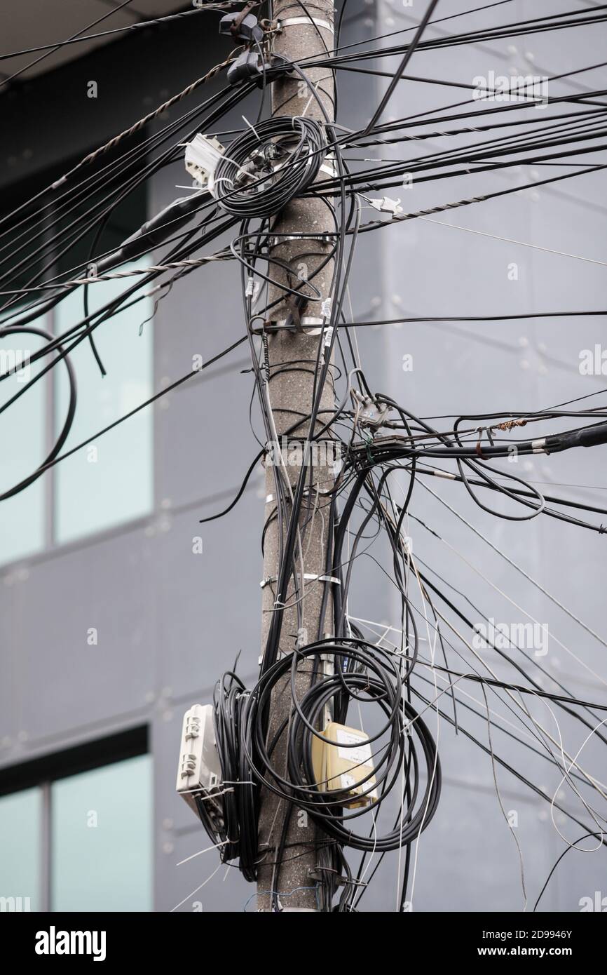 Many unorganised internet and TV cables on a concrete pole in Bucharest. Stock Photo