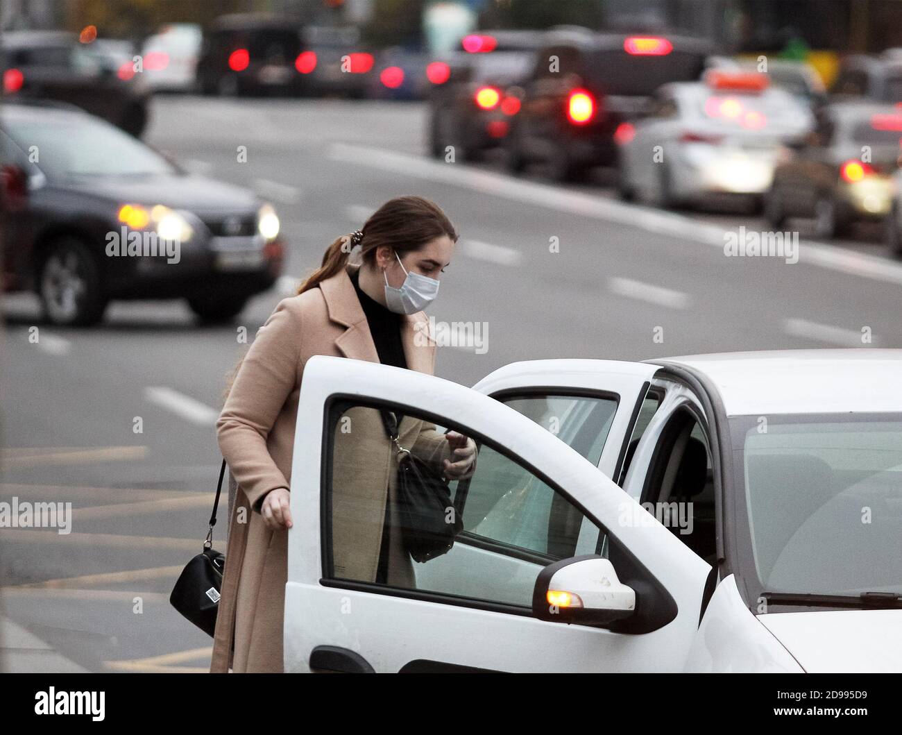 A woman wearing a face mask as a precaution getting into a taxi in