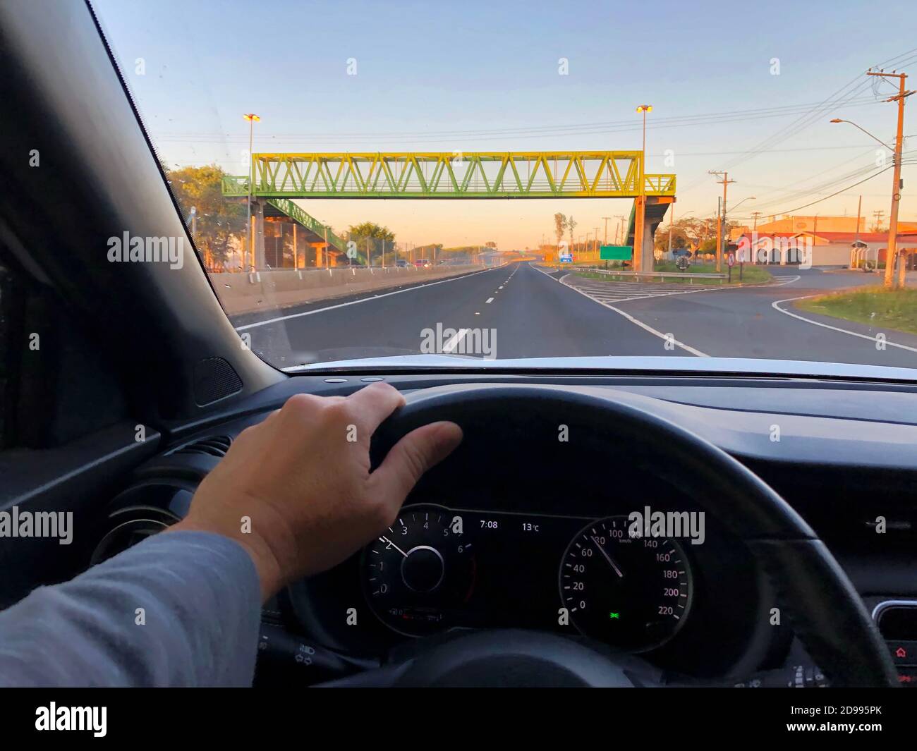 A driver's point of view at sunrise, on a motorway with a pedestrian walkway. Stock Photo