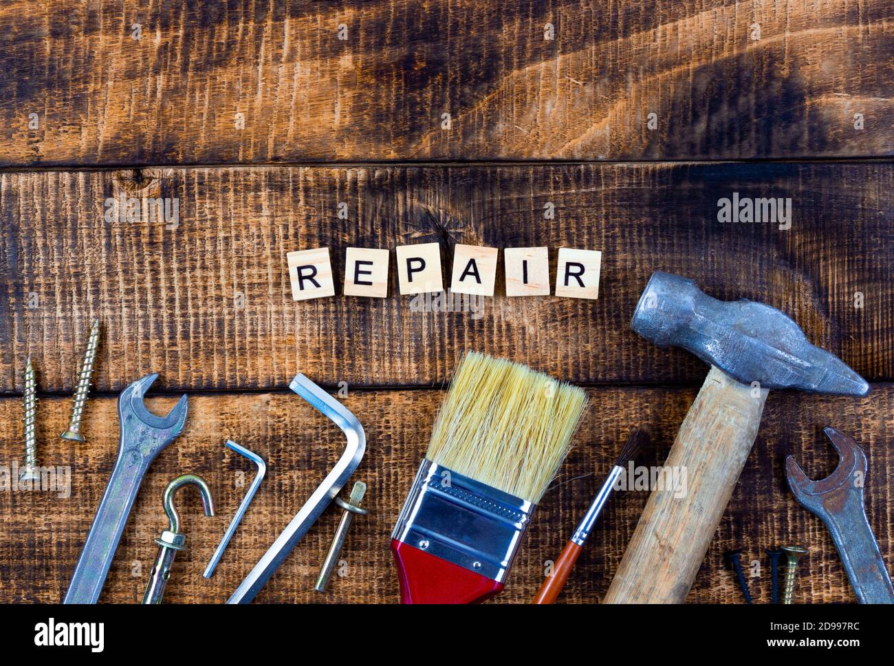 different working tools brush hammer wrench screwdriver. Repair word on wooden background. Stock Photo