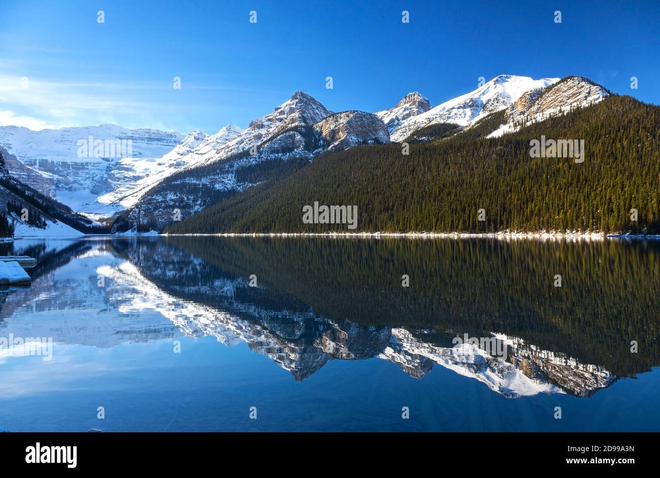 Scenic Landscape View of Lake Louise Shore with Rocky Mountain Peaks reflected in Calm Blue Water, Banff National Park, Canadian Rockies Stock Photo