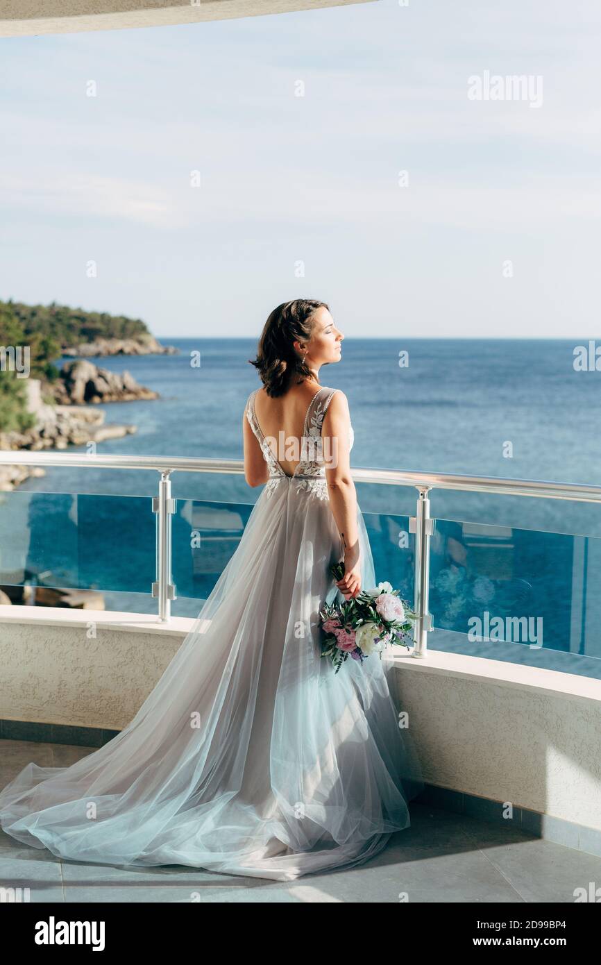 the bride in a beautiful wedding dress stands on the balcony ...