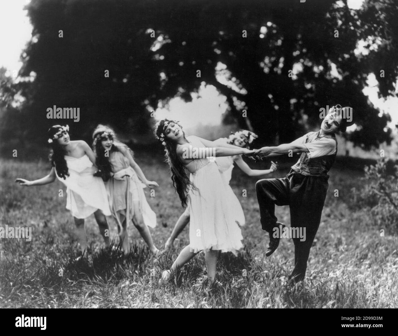 1919 , USA : The movie actor and director CHARLES  CHAPLIN  ( 1889 - 1977 ) as CHARLOT in shot movie SUNNYSIDE ( L'idillio nei campi ) by  Charles Chaplin  , with  Edna Purviance and  Olive Ann Alcorn . - DANCE - SMILE - SORRISO - DANZA - prato - grass - ninfa - ninfe - CINEMA MUTO - SILENT MOVIE  ----    ARCHIVIO GBB Stock Photo