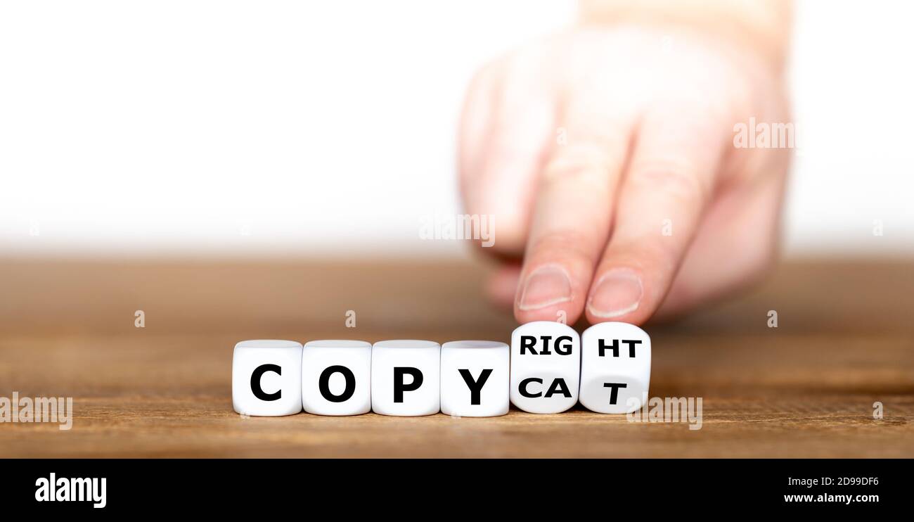 Hand turns dice and changes the word 'copy cat' to 'copyright'. Stock Photo