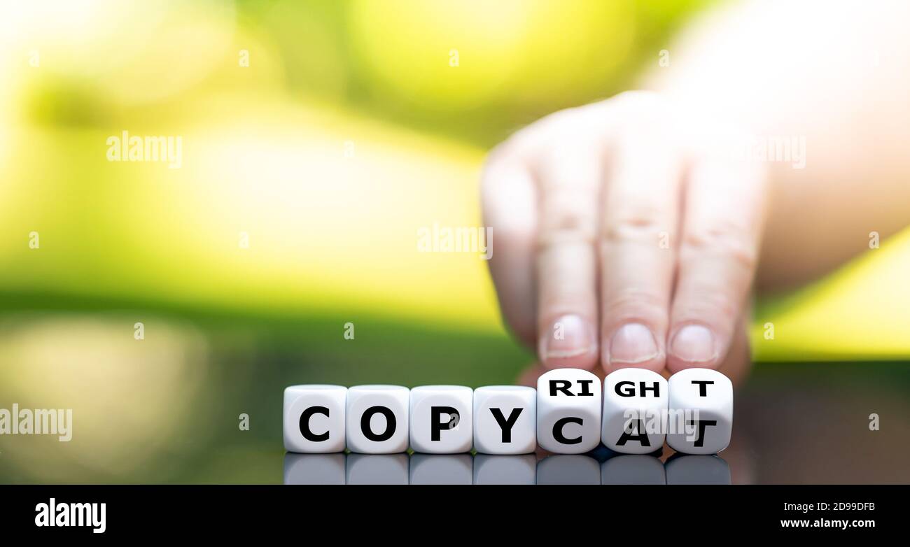 Hand turns dice and changes the word "copy cat" to "copyright". Stock Photo