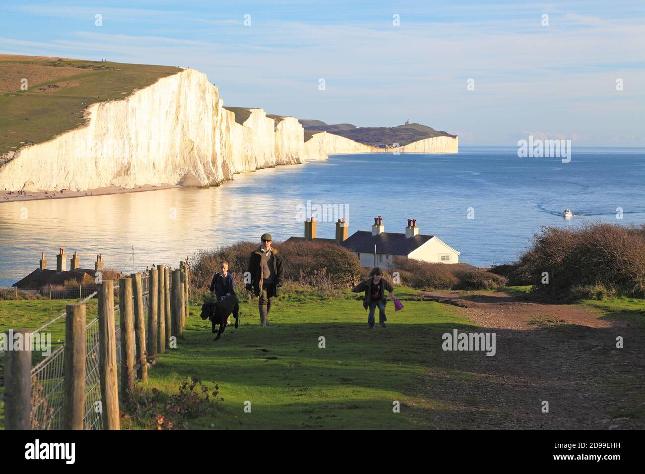 Walkers on the South Downs Way with the Seven Sisters chalk cliffs and coastline , East Sussex, UK Stock Photo